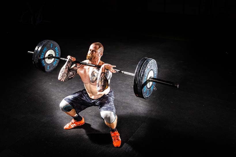 man squating with barbell strength training