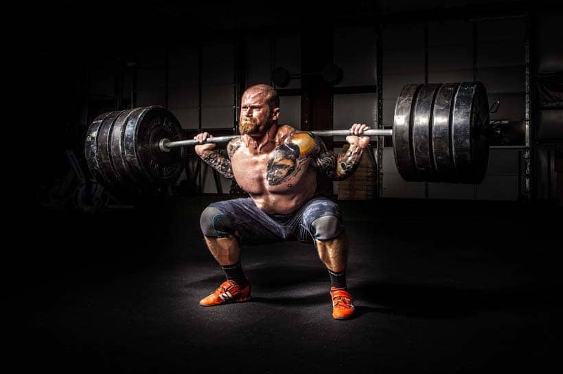 man strength training with heavy squats