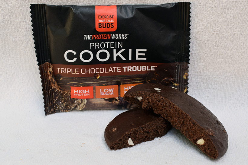 The protein works protein snacks Protein cookie triple chocolate trouble Flavour packaging with close up cookie inside